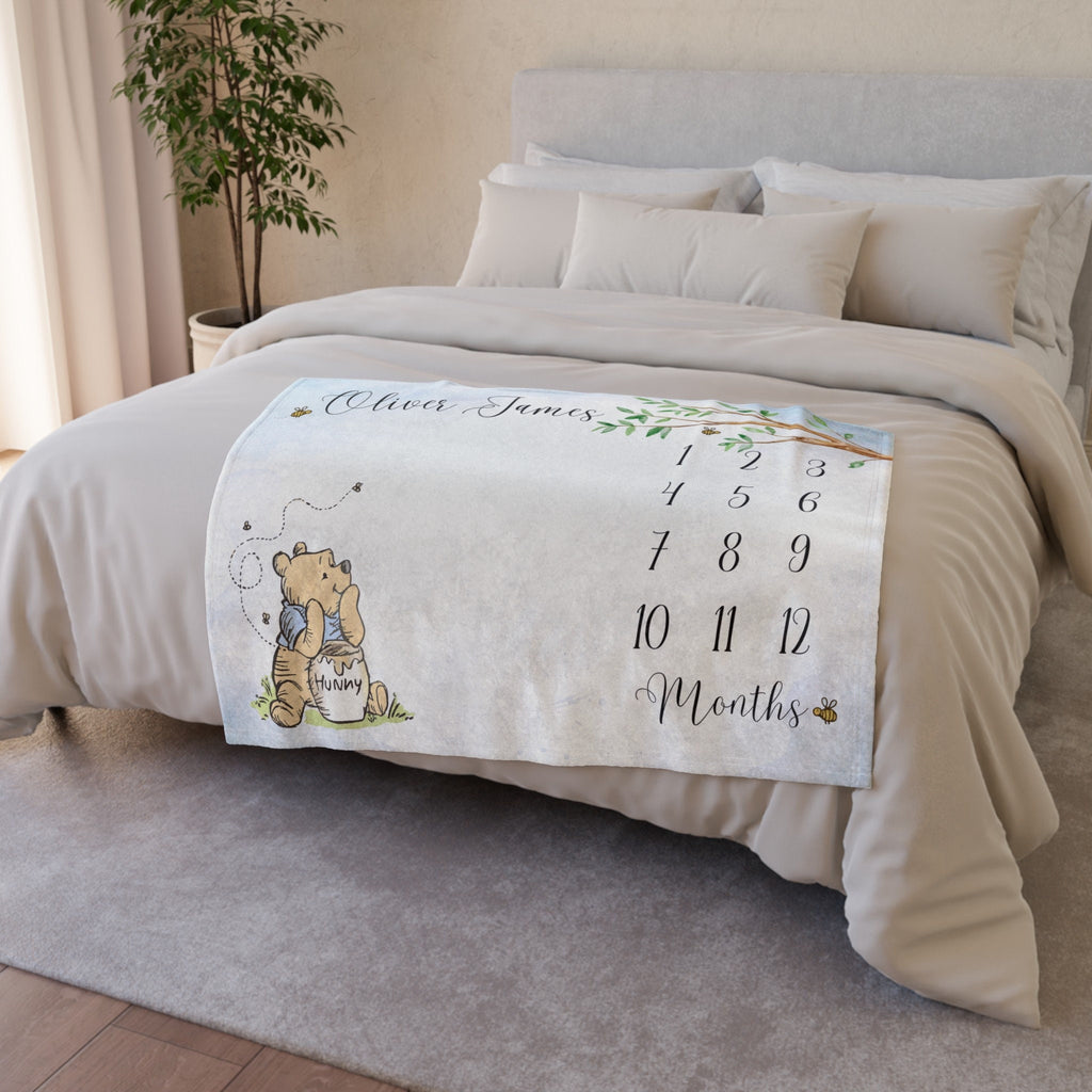 Storybook Winnie the Bear themed baby milestone blanket with a light blue background. The blanket features a drawing of classic storybook teddy bear holding a honey pot. Minky fleece 40x30 inches.