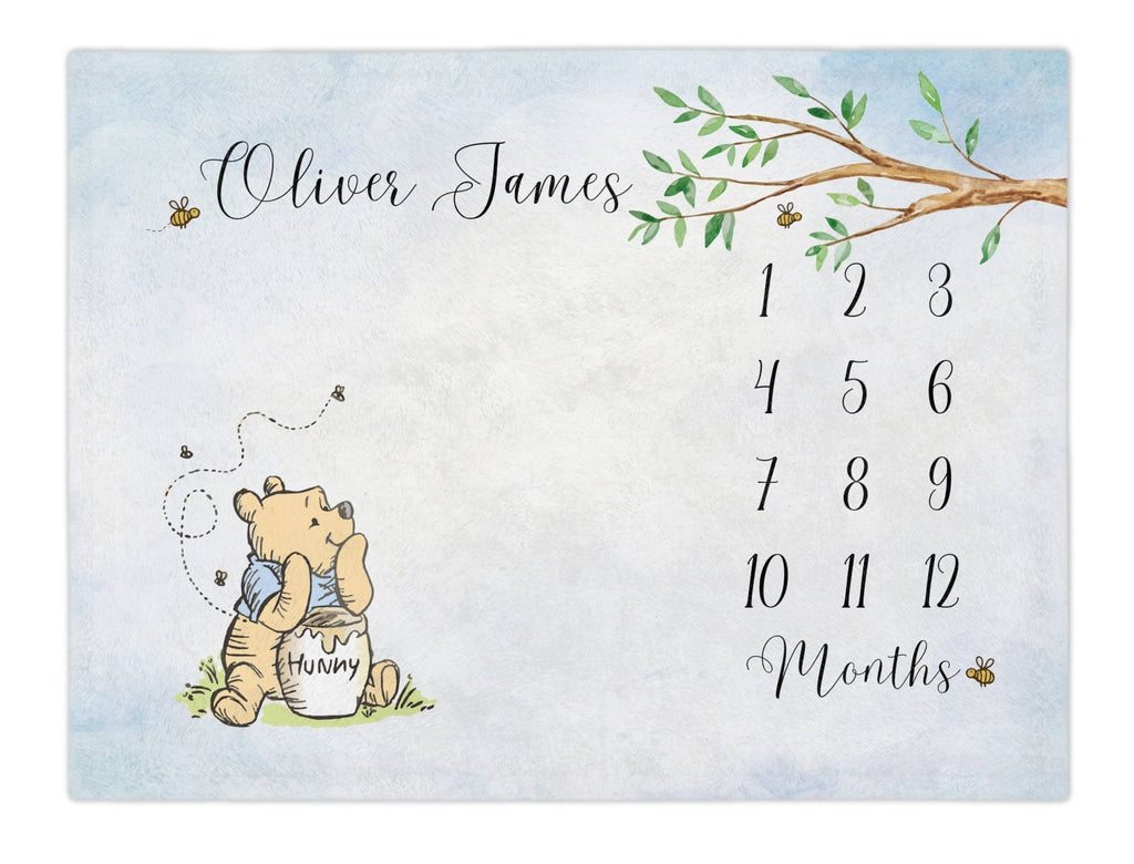 Classic Storybook Bear baby milestone blanket. Classic Winnie the bear inspired monthly growth blanket. The winnie bear has a blue shirt. The blue watercolor hue, bumble bees make this an adorable baby shower gift for baby boy. baby month blanket. Calendar monthly Growth blanket.