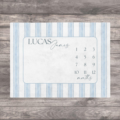 Blue Heirloom Stripe Baby Milestone Blanket. Baby Milestone Blanket Boy, Personalized Month Blanket Blue Striped, Preppy Monthly Growth Mat, Custom Baby Shower Gift. A rectangular milestone blanket with a light blue and white striped border. The center features a light blue frame with the name "LUCAS James" and numbers 1-12 with the word "months" below.