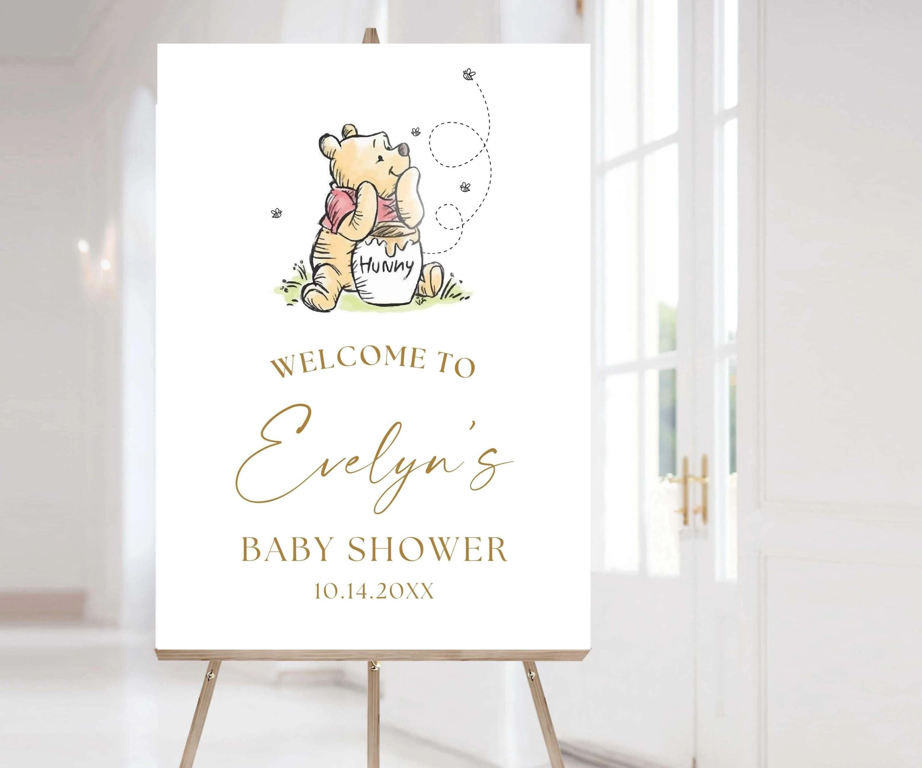May include: A Winnie the Pooh themed baby shower welcome sign with a cartoon illustration of Winnie the Pooh holding a honey pot. The sign says "Welcome to Evelyn's Baby Shower 10.14.20XX".