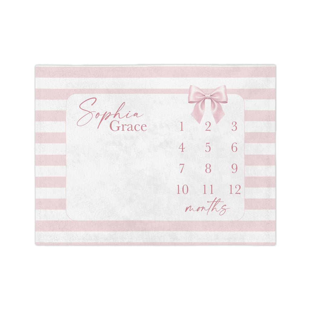 May include: A rectangular baby milestone blanket with a pink and white striped border. The center features a white space with the name "Sophia Grace" in cursive, a pink bow, and numbers 1-12 with the word "months".