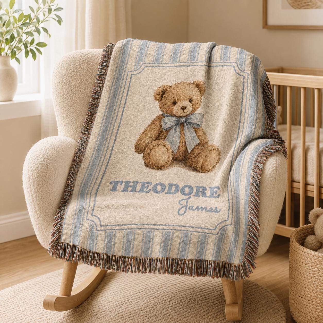 Personalized blue striped cotton woven baby blanket laid on a chair inside a neutral nursery, featuring a brown teddy bear with a dusty-blue bow, custom name, framed design and fringed edges.