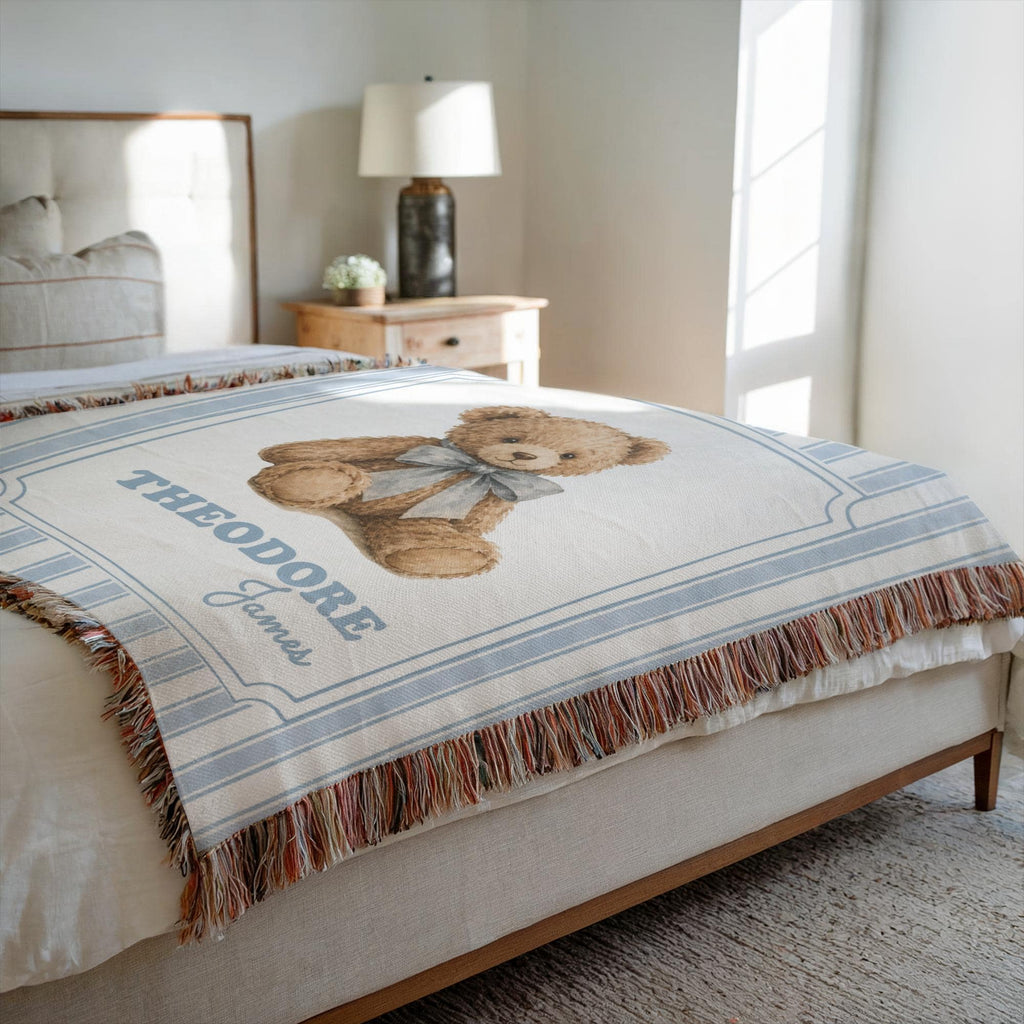 Heirloom Woven Teddy Bear Blanket with blue stripes laid flat on a neutral bed.