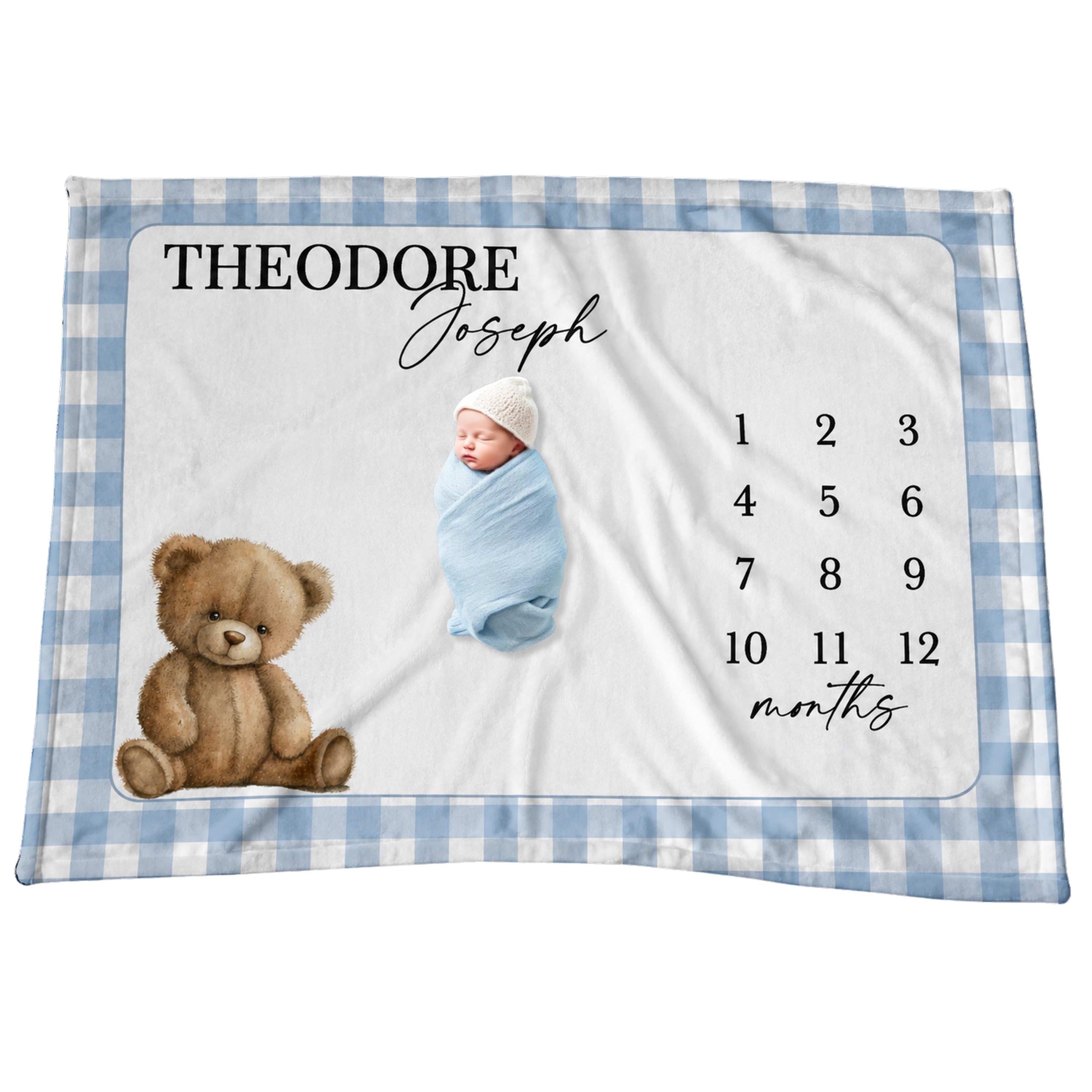 Close-up of a baby laying on a milestone blanket showing the detailed blue gingham pattern, teddy bear illustration and with script text.