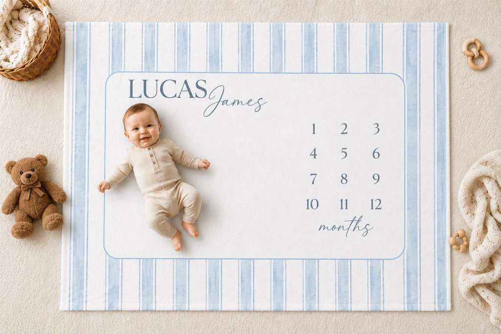 Personalized blue striped baby milestone blanket with watercolor stripes, featuring a soft medium brown teddy bear, neutral nursery styling, and a smiling baby lying on a custom monthly milestone blanket for newborn photos.