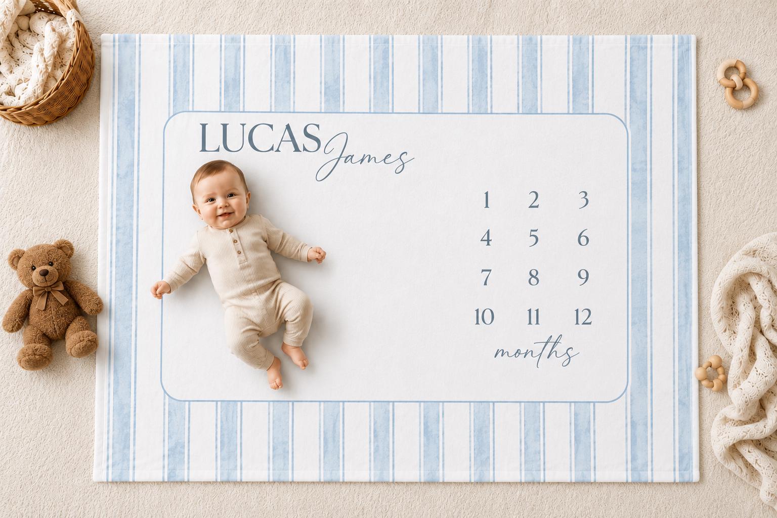 Personalized blue striped baby milestone blanket with watercolor stripes, featuring a soft medium brown teddy bear, neutral nursery styling, and a smiling baby lying on a custom monthly milestone blanket for newborn photos.
