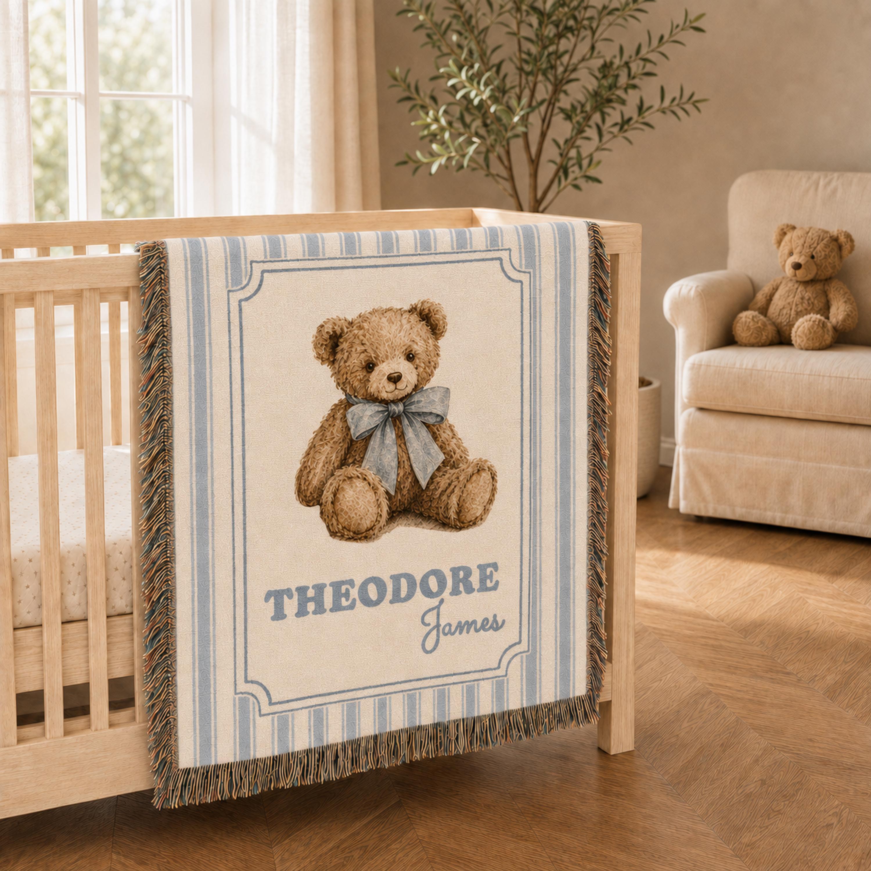 Bright neutral nursery featuring a personalized blue striped vintage style woven teddy bear blanket hanging from a light oak crib near a window, tall plant, and cream armchair.