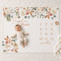 A cheerful baby lays smiling on a fall themed personalized monthly milestone blanket featuring an earth tone Terracotta Rose & Neutral Eucalyptus Boho floral border with the name "Sophia Marie" printed on it.